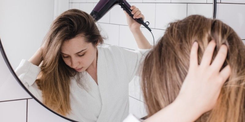 Woman blow drying her hair in a mirror