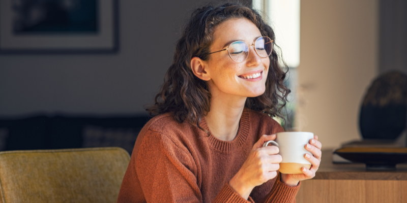 Woman smiling and holding a warm coffee mug