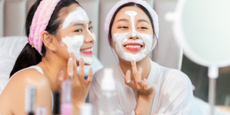 Two young woman putting on skin care face masks