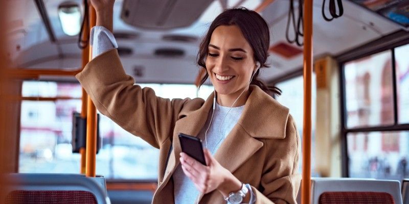 Woman smiling at phone on public transportation