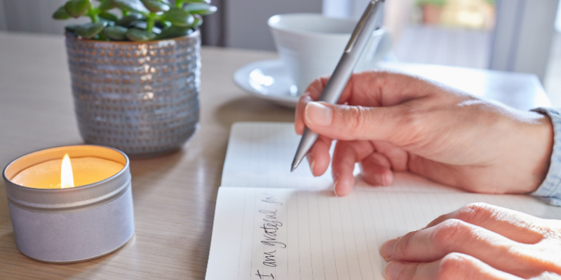 Woman journaling next to a candle and plant